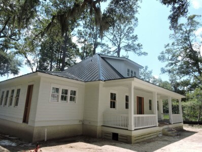 Side view of a white, paneled house with onyx metal roofing