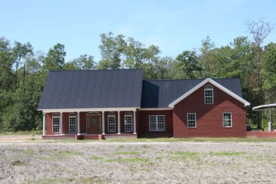Red, brick-walled house with an onyx rib metal roofing